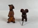 two small wooden sculptures of dogs on a white surface