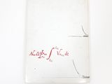 an old book with red writing on it sitting on top of a white surface