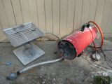 a red fire extinguisher sitting on the ground next to a metal grill