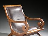 a wooden chair with leather upholstered seat and foot rest