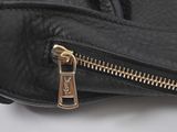 the zipper of a black leather purse with a gold zipper