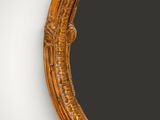 an oval mirror with a carved frame and a black background