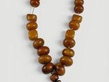 un collier en perles de bois dont l'extrémité est ornée d'un pompon