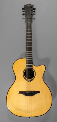un gros plan d'une guitare acoustique sur fond gris