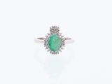 gros plan d'une bague avec une pierre verte entourée de diamants blancs