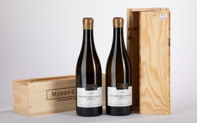 deux bouteilles de vin dans un coffret en bois à côté d'une bouteille de vin