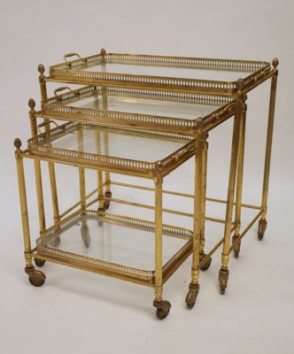 a pair of brass and glass nesting tables on casteors