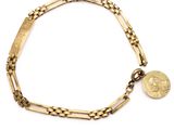 Gros plan sur un bracelet en or orné d'une pièce de monnaie
