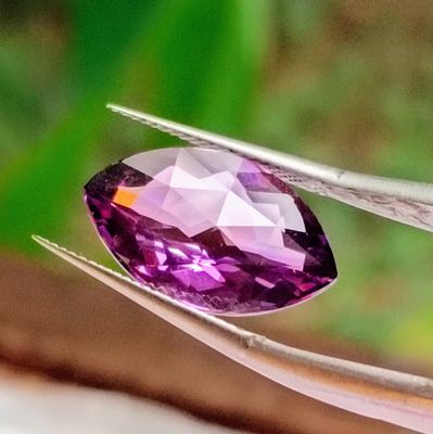 someone holding a pair of pliers with a purple gemstone on it