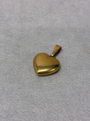 a small gold heart pendant on a white surface