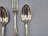 three silver spoons and a fork on a gray surface