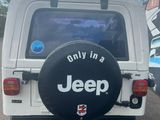 a white jeep with a black tire cover parked in a parking lot