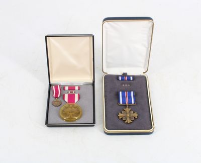 two medals and a medal in a box on a white surface