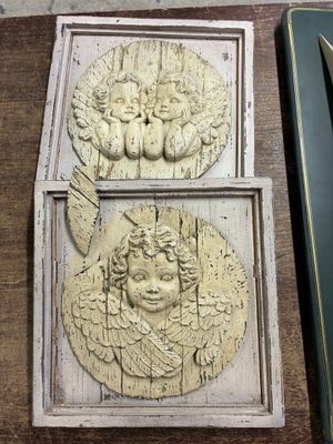 deux plaques représentant des anges posées sur une table en bois