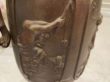 a bronze vase with a bird on it sitting on a table