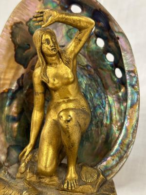 statue en laiton représentant une femme dans un coquillage, avec un coquillage en arrière-plan