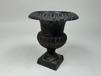 a black vase that is sitting on a white surface