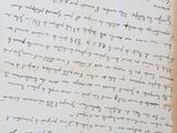 an old manuscript with writing on it sitting on top of a wooden table