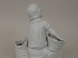 a white statue of a girl sitting on a basket