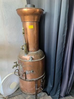 a large copper pot sitting on top of a metal stand