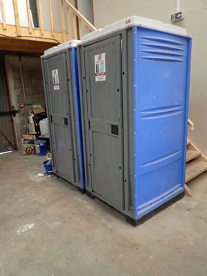 deux toilettes portables dans un garage équipé d'un escalier