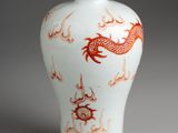 a white vase with a red dragon design on it