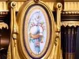 a gold clock on a table with a picture on it