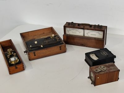 trois boîtes en bois contenant différents types d'appareils électroniques, posées sur une surface blanche