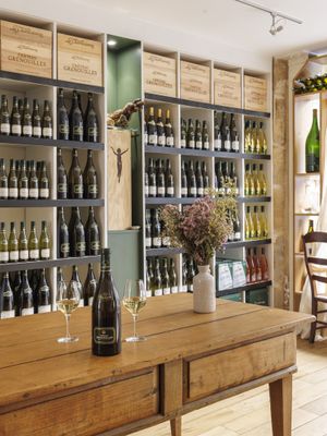 bottles of wine and glasses on a table in front of a wall of wine bottles