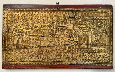 an old gold plate with a painting on it hanging on a wall