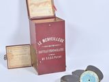 une boîte rouge avec une étiquette, posée à côté d'une paire de dessous de verre