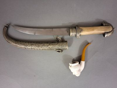 une vieille dague, accompagnée d'une pipe et d'un porte-pipe, posée sur une table