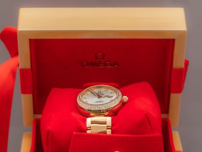 une photo d'une montre en or dans un coffret rouge, avec une cravate rouge