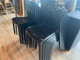 quatre chaises en plastique noir posées sur un parquet