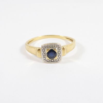 an image of a gold ring with a sapphire and diamonds