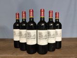 six bottles of red wine are lined up on a wooden table
