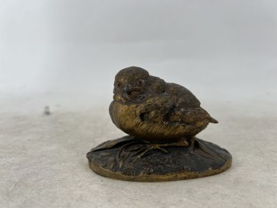 a small bronze bird sitting on top of a wooden base