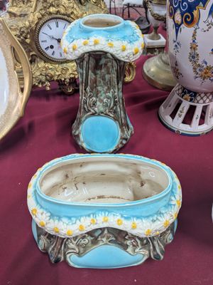 de nombreux vases de toutes sortes posés sur une table, avec une horloge en arrière-plan