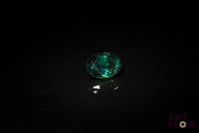 un gros plan d'un objet en verre vert posé sur une surface noire