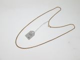 une chaîne en or à laquelle est accrochée une médaille, posée sur une surface blanche