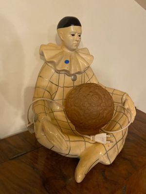 a ceramic figurine of a clown holding a ball on a wooden floor