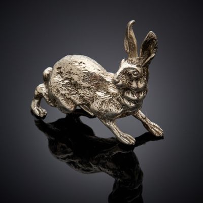 une figurine de lapin en argent posée sur une surface noire