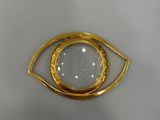 a close up of a gold and white eye broochle on a white background