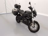 une moto noire garée dans une pièce aux murs blancs