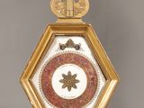 a gold and red clock with a bird on top of it