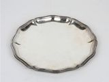 une assiette ancienne en argent, avec un bord décoratif sur une surface blanche