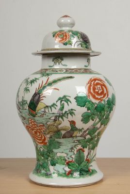 un vase muni d'un couvercle posé sur une table en bois