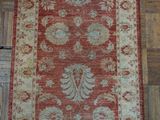 a red and beige rug on a wooden floor in a room