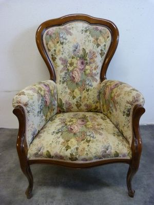 une chaise avec un dossier et des accoudoirs tapissés de fleurs