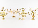 four brass candelabs with flowers and leaves on them